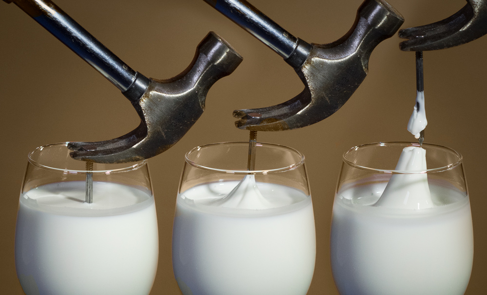 An image showing 3 stages of a hammer pulling a nail out of a glass filled with a cornstarch mixture