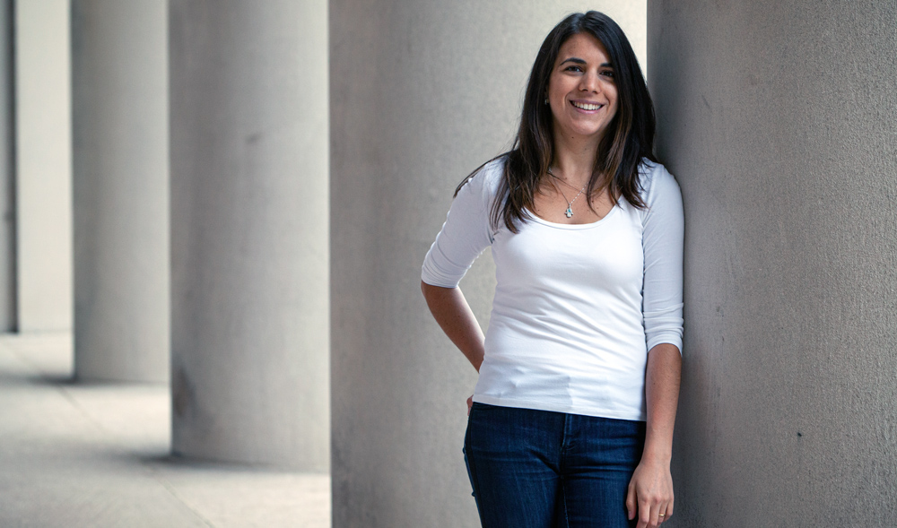 Cecilia Testart leaning against a large stone column on MIT's campus