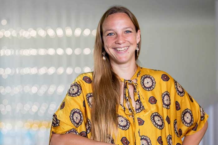 Head and shoulders portrait of Mariel Borowitz ’06 wearing a patterned yellow shirt in front of a white background dotted with lights