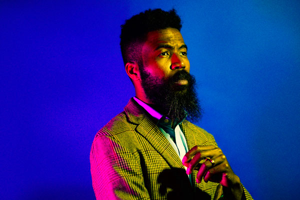 Joshua Bennett with pink lighting and blue background