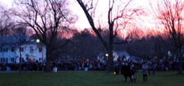 The view to the east as the sun rises.  You can people watching on the far side of the green.  The building in the background is the Masonic lodge.