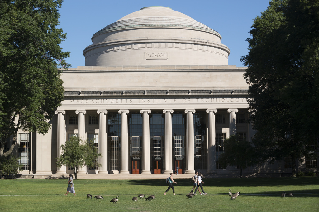 Several people walk on the lawn in front of the Great Dome.