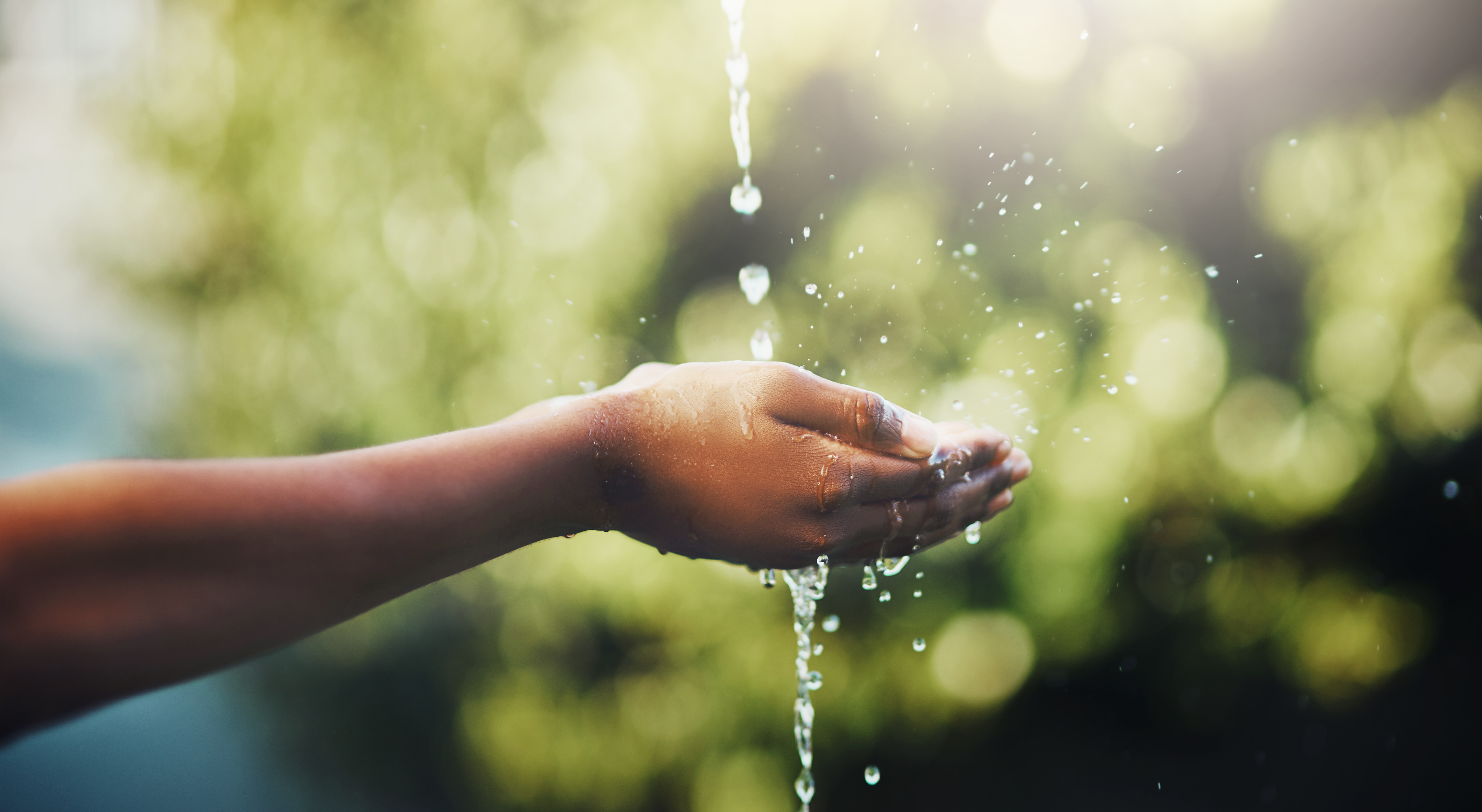 A stream of water falls into an outstretched hand.