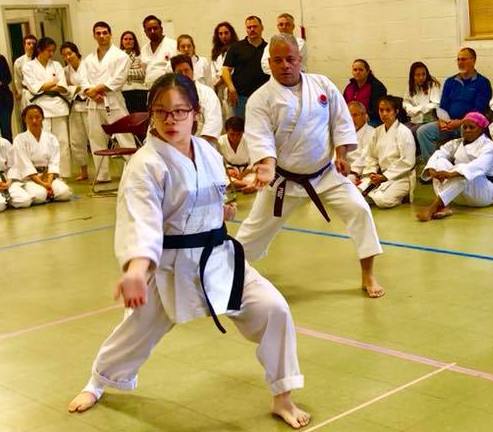 Two members of the karate club compete while other participants look on from behind.