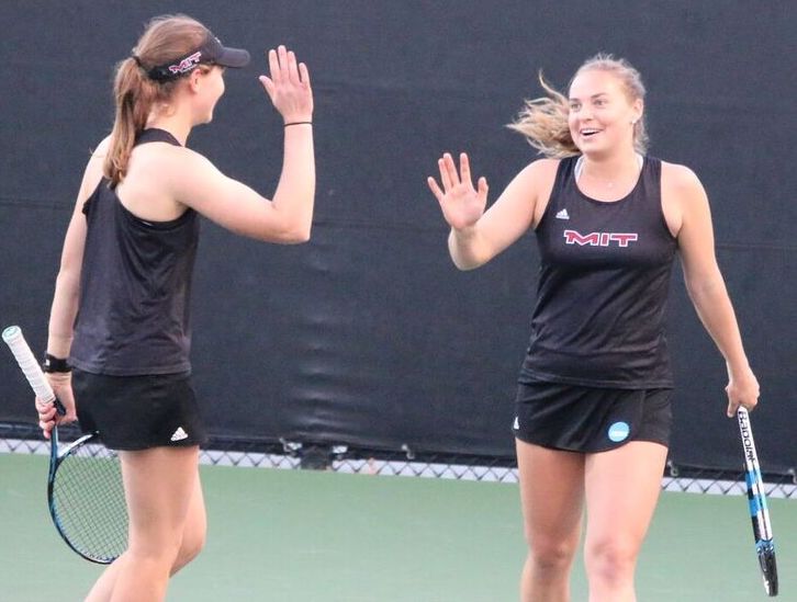 Two tennis players give each other a high five.