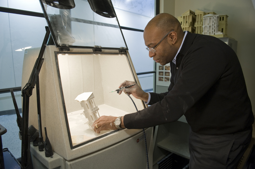 A professor looks at a model under a bright light.