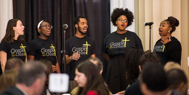 Five members of the MIT Gospel Choir perform in front of a crowd.