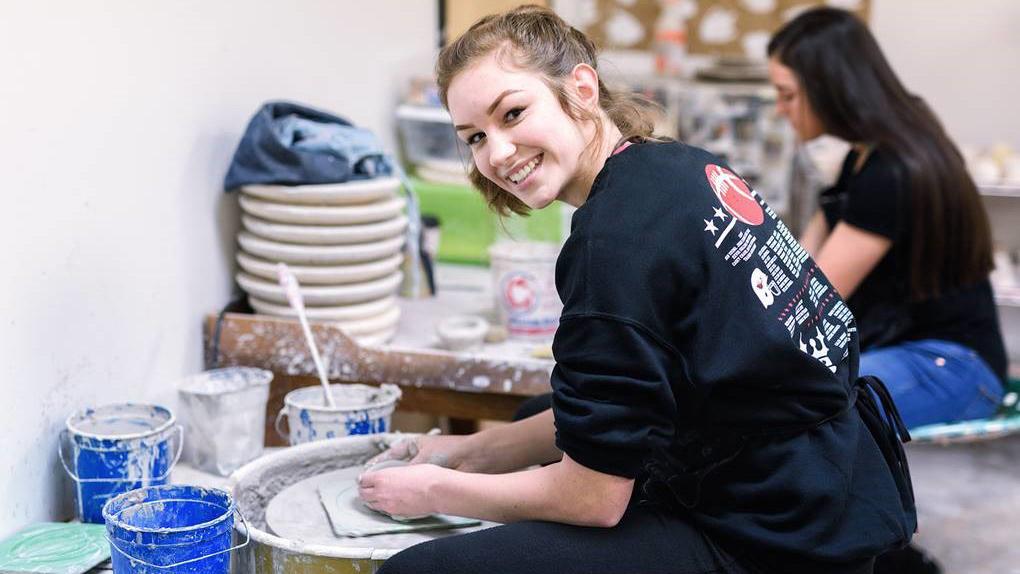 photograph of a young woman working on a pottery wheel