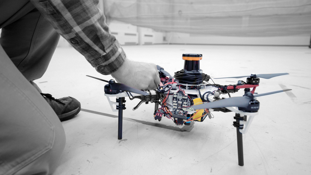 a photograph of a drone being looked at by one of the MIT research team