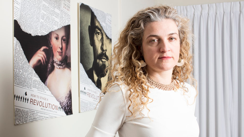 An image of Lerna Ekmekcioglu in front of two posters