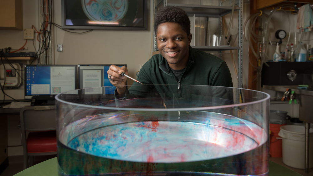 An image of Jordan Benjamin dropping colored ink into a basin of water