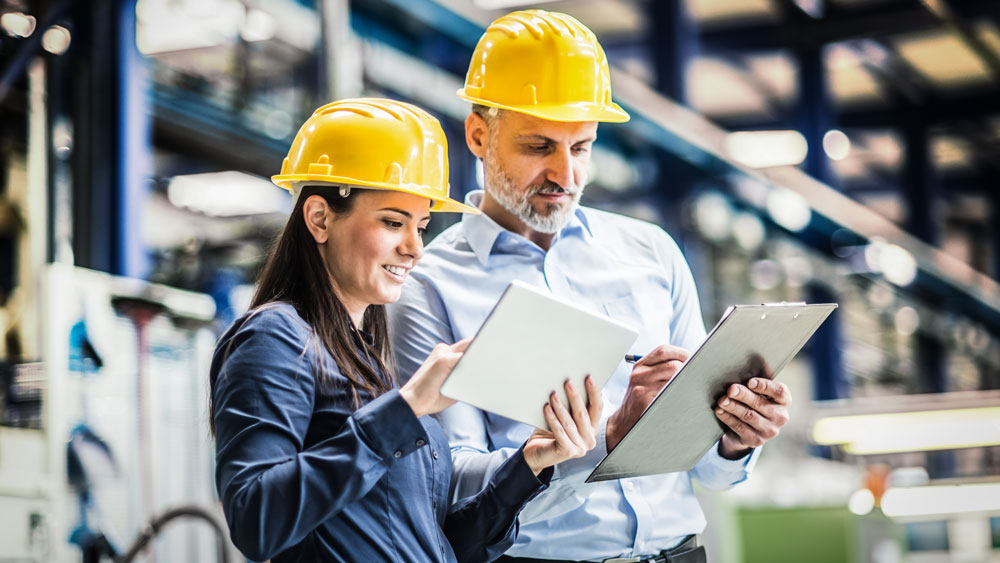 two people in hard hats working in a manufacturing factory