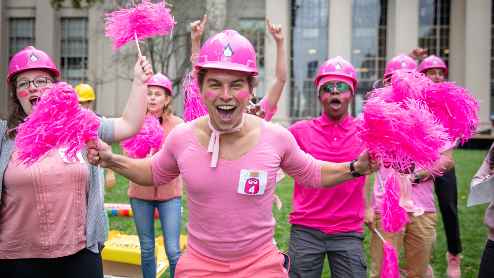 Team dressed in pink yelling and holding pink pompoms