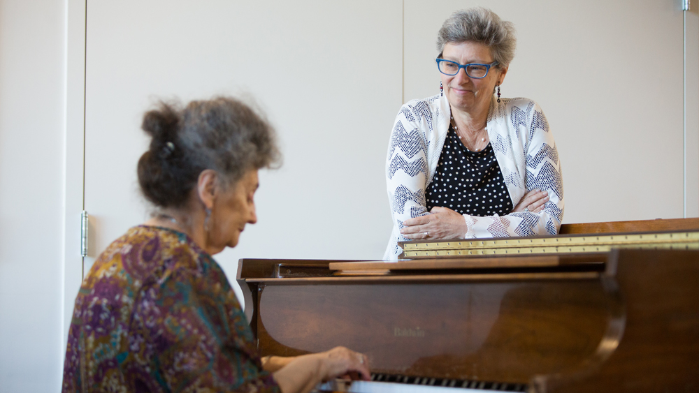 At 2Life’s campus in Brighton, Massachusetts, Amy Schectman watches resident Tatyana Faynberg playing the piano