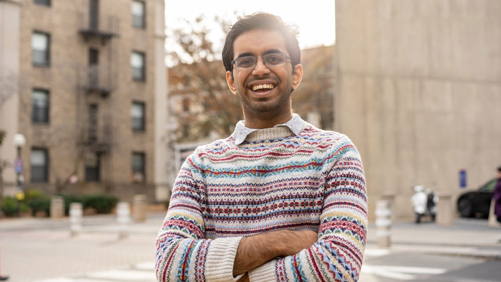Tarun Kamath standing outside on MIT's campus with the shining behind him