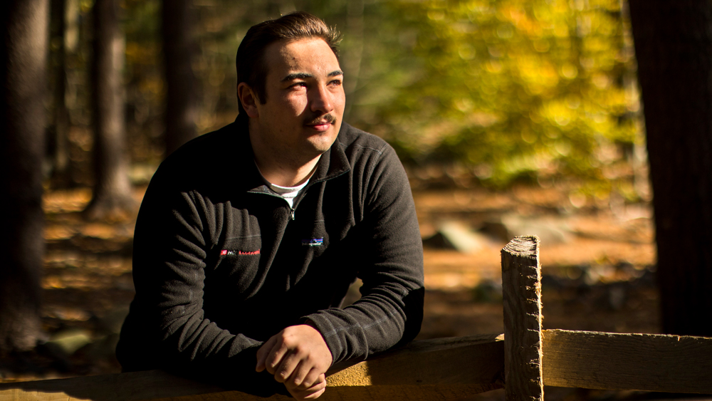 Benjamin Delhees leaning on fence outside, by Adam Glanzman