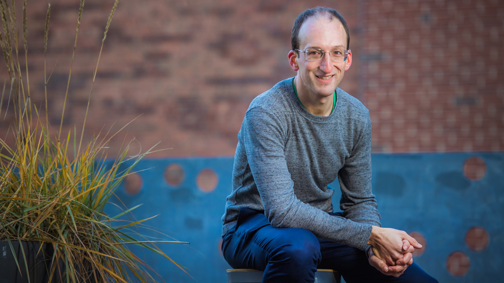 Michael Short sitting in front of a brick wall