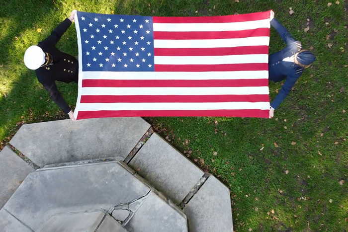 An aerial view of two ROTC cadets holding an American flag open