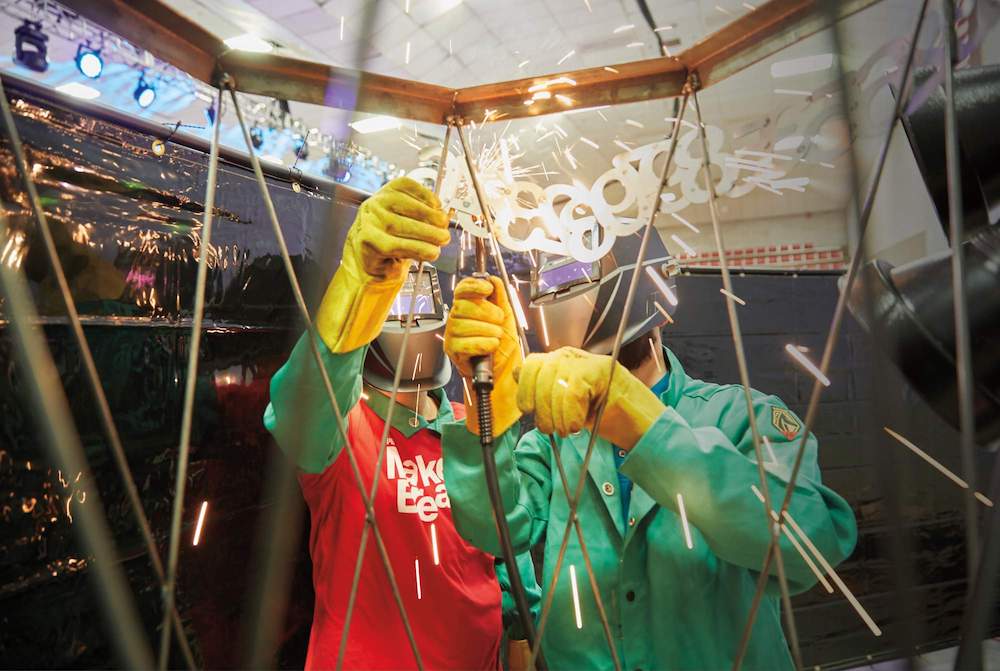 Two students weld steel numerals while making a sculpture.