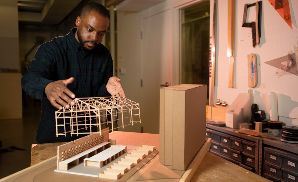 Justin Brazier places a wooden model of a house on a table