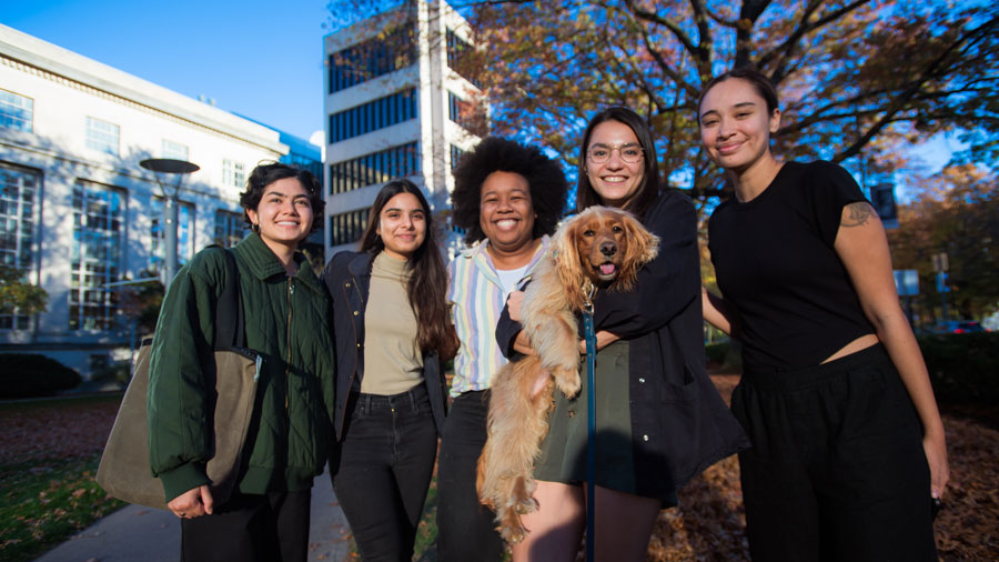5 people and a cute puppy pose for a photo with Green Building in background
