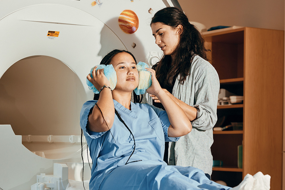 Saima Malik-Moraleda prepares a lab colleague for an MRI imaging session and reviews brain images