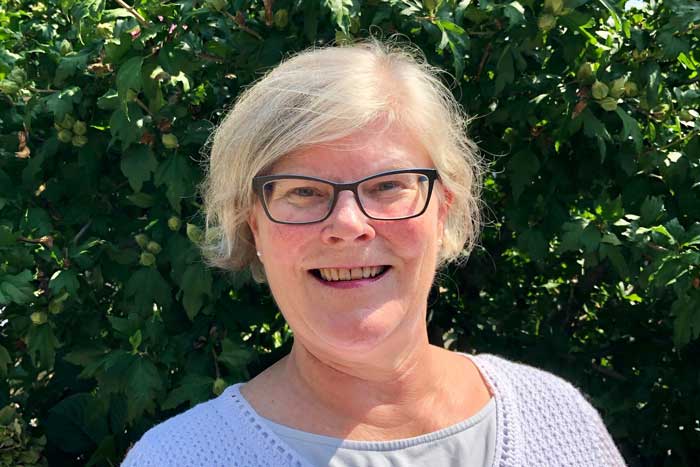 Kim Vermeer outside with green foliage is background