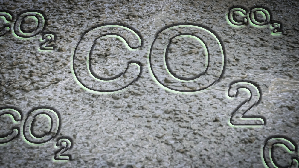 Embossed letters say “CO2” on wet cement background.