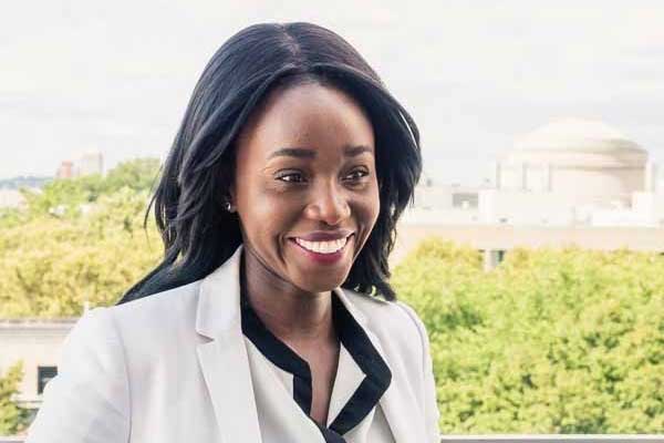 Ezinee Uzo-Okoro is pictured outside, smiling and gazing off to the right. Green trees and the MIT dome are in the background