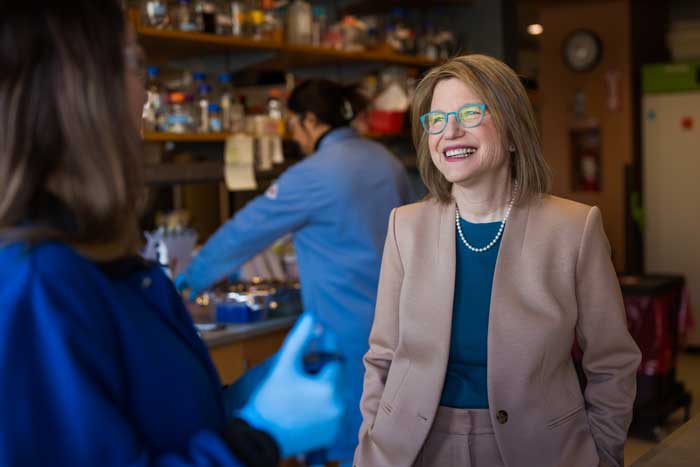 Kornbluth in conversation with MIT student inside a busy MIT lab