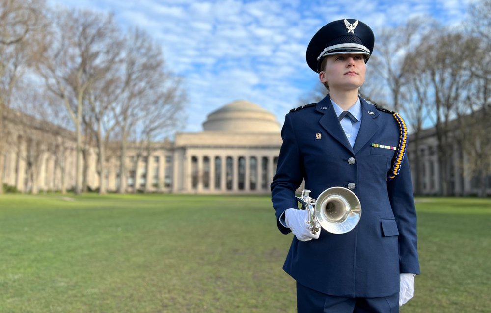 Air Force ROTC Cadet Morgan Schaefer holding a trumpet and standing in Killian Court at MIT