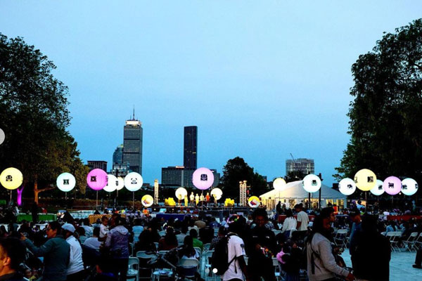 a crowd of people in Killian Court at dusk surrounded by colored globe lights 