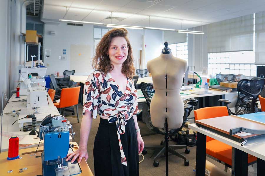 Ganit Goldstein stands in one of MIT's textile spaces. Sewing machines and a mannequin are visible in the background.