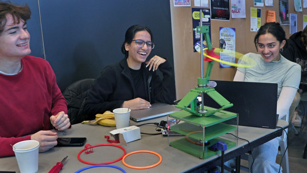 Students Michael Burgess (left), Sharmi Shah (middle), and Maheera Bawa (right) enjoy the fruits of their labor in the form of their hula-hooping robot, Hula Hooper, performing a successful demonstration