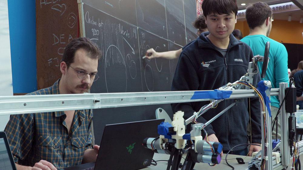 Erik Ballesteros (left), Roberto Bolli (right), demonstrate their robot’s walking gait during the classes final project exhibition.