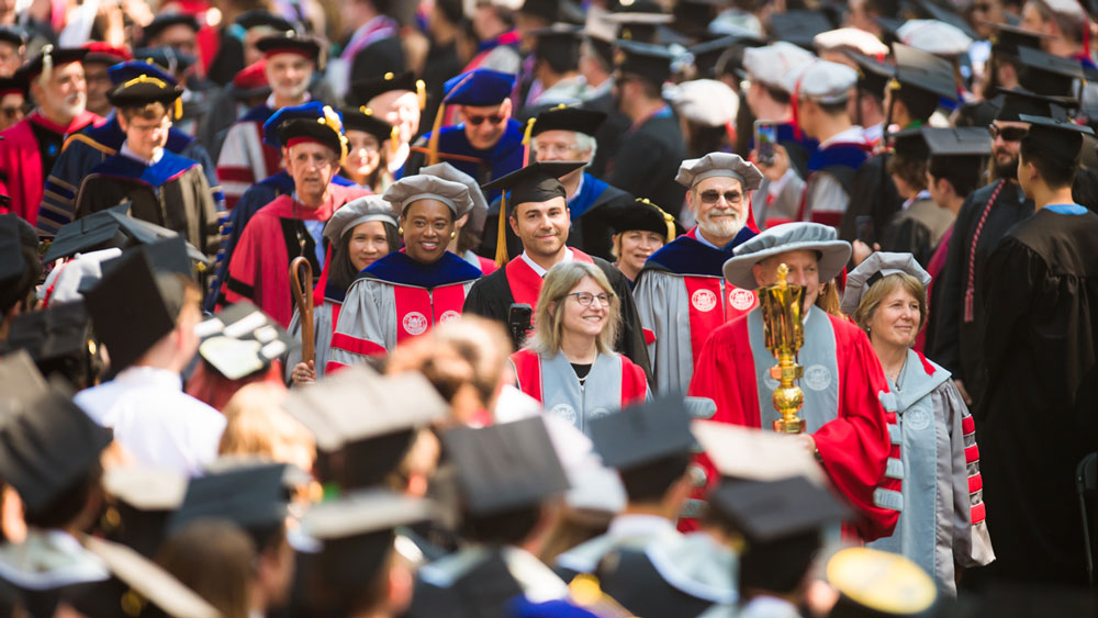 President Sally Kornbluth and speaker Mark Rober, along with many MIT members, in a procession surrounded by graduates