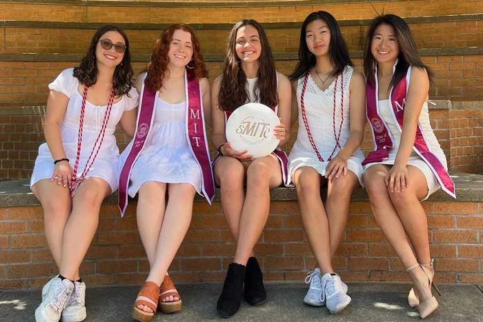 5 members of the MIT Women’s Ultimate team pose for a group photo with a frisbee at the Dertouzos Amphitheater near Stata