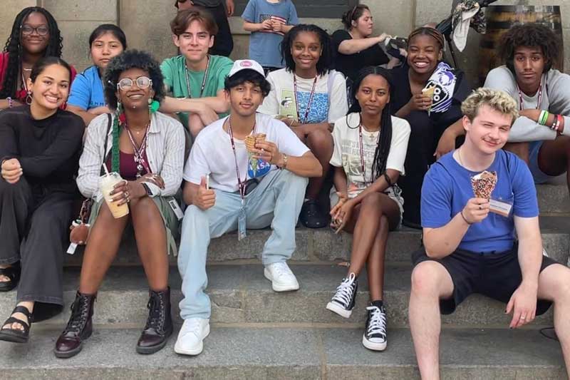 About 11 MITES students relax on the steps with ice cream