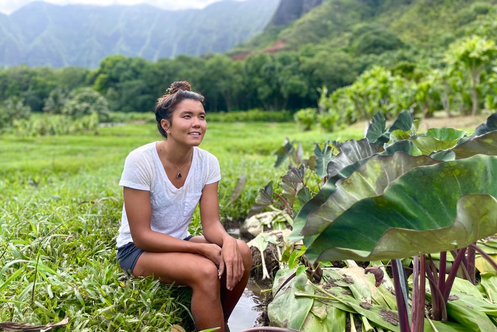 Aja Grande sitting near native crops in Hawaiʻi