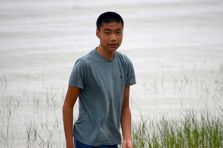 Dustin Liang stands outside, with water and grass in background