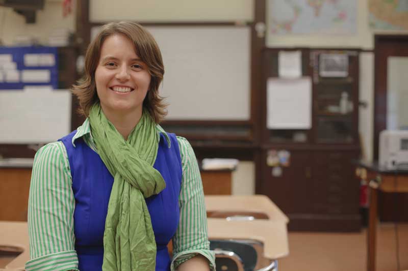 Shannon Morey smiles, with blurring classroom in background