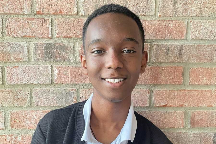 High school student Thomas Esayas smiles, with brick background