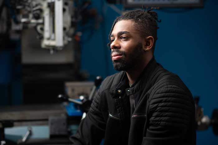 Baran Mensah portrait with blue background in lab.