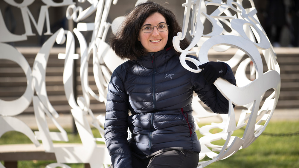 Tamara Broderick sits on The Alchemist sculpture on campus