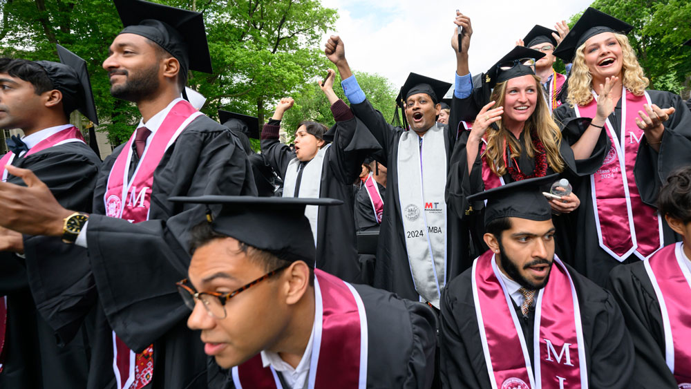 Smiling MIT graduates in regalia at Commencement