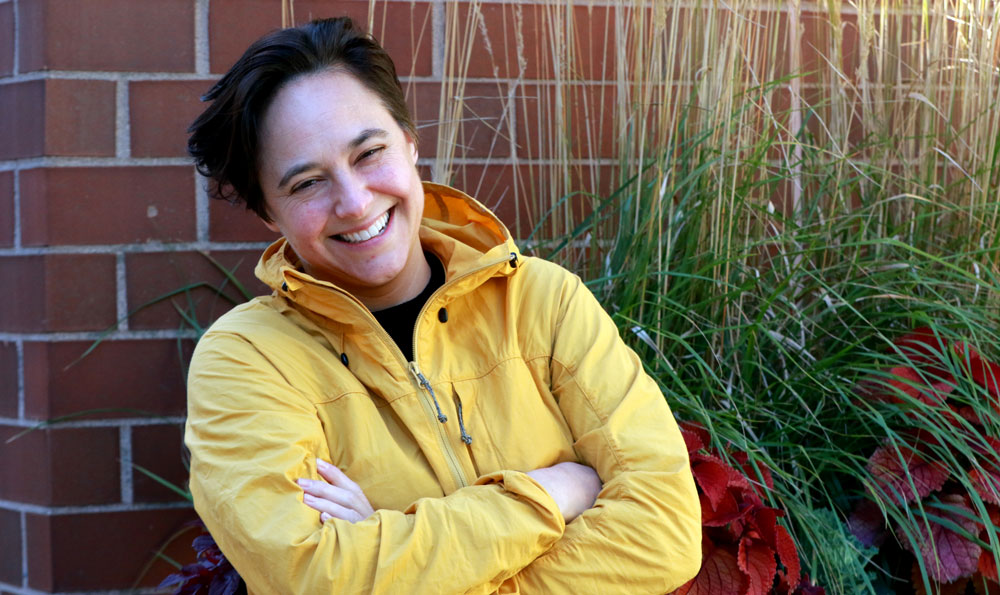 Caley Horan portrait outside with brick wall and foliage