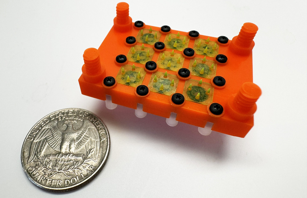 The 3D-printed device has a 3x3 array of cone-shaped emitters, and is next to a quarter showing that it’s about twice the size.