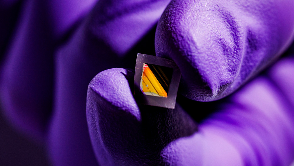 Gloved hand hold tiny square material with golden reflection