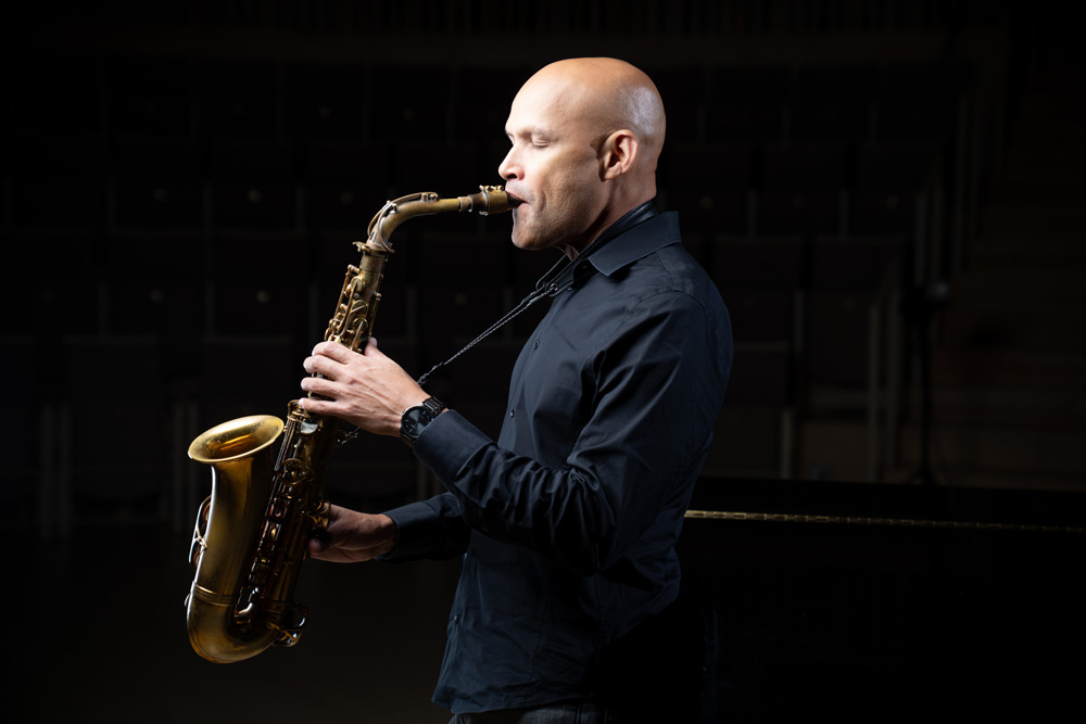 Side-view of Miguel Zenon playing saxophone in dark music room
