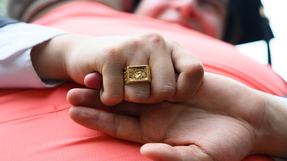 A closeup hug at Commencement, showing a grad's Brass rat ring